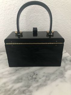 Vintage Maxim Black Acrylic Handbag 1950’s. Shipped with USPS Priority Mail. Black acrylic with gold tone hardware . Mirror shows age and there are surface scratches. Has 2 separate compartments ... top one opens & has the mirror. Then the next one slides up & out so you have 2 levels. Very cute bag . 7 x 3”. 4.25” to top of box & 9” to top of handle Black Acrylic, Black Acrylics, Cute Bag, Kate Spade Top Handle Bag, Priority Mail, Slides, Top Handle Bag, Gold Tones, The Next