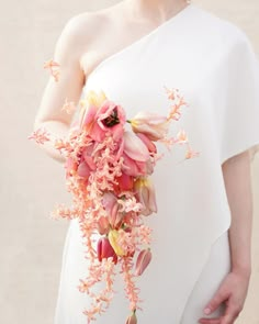 a woman holding a bouquet of flowers in her hand and wearing a white dress with pink flowers on it