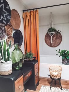 a living room filled with lots of plants next to a bathtub covered in wicker baskets