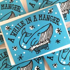 several blue greeting cards with black and white designs on them, one has an image of a whale in a manger