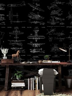 a desk with some books on it in front of a black wall that has drawings all over it