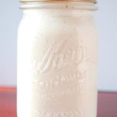 a mason jar filled with white liquid sitting on top of a wooden table