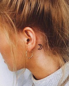 a woman with a small crescent tattoo on her left side of her neck and behind her ear