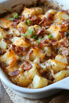 a casserole dish with potatoes, bacon and green onions in it on a wooden table