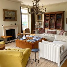 a living room filled with lots of furniture and a chandelier hanging from the ceiling