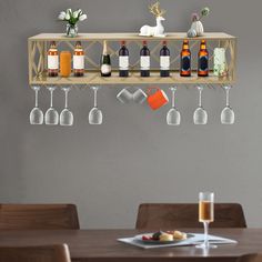 a wooden shelf with wine glasses and bottles hanging from it's sides on the wall