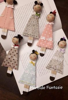 paper dolls sitting on top of an open book with the pages folded down to make them look like they are wearing dresses