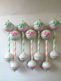 there are many candy lollipops with bows on them and one is pink and green