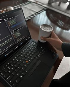 a laptop computer sitting on top of a wooden table next to a cup of coffee