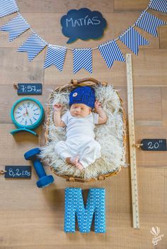 a baby is laying in a basket next to a clock and other items on the floor