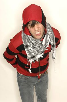 a young man wearing a red hoodie and scarf with his hands in his pockets