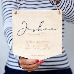 a woman holding up a wooden sign with the name of her wedding date on it