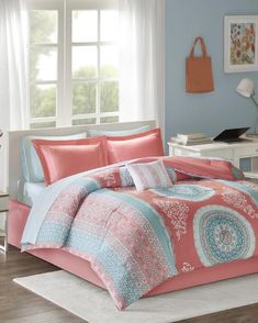 a bedroom with blue walls and pink comforter sets on the bed in front of a window