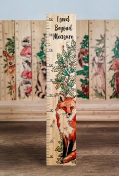 a tall wooden ruler with a fox on it's face and the words loved beyond measure