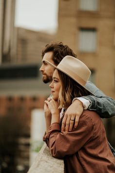 a man and woman standing next to each other with their arms wrapped around one another