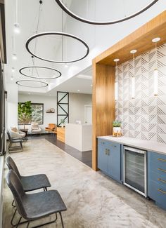 an empty room with chairs and cabinets in the center is lit by pendant lights hanging from the ceiling