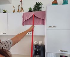 a woman is cleaning the kitchen with a pink cloth on top of an oven door