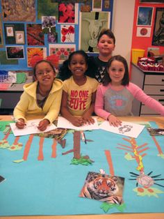 four children sitting at a table with pictures on it