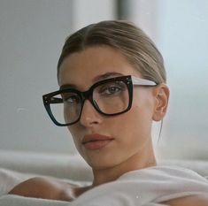 a woman wearing glasses laying on top of a bed