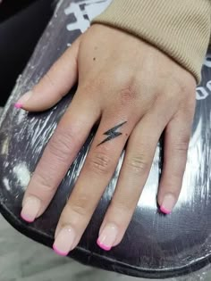 a woman's hand with a small black arrow tattoo on her left ring finger