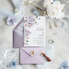 the wedding stationery is laid out on top of an envelope, with flowers and ribbons around it