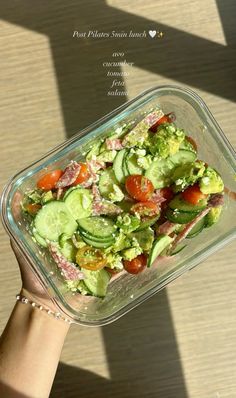 a person holding up a glass dish filled with vegetables