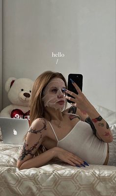 a woman laying on top of a bed next to a teddy bear holding a cell phone