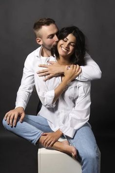 a man and woman hugging each other while sitting on top of a white box stock photos