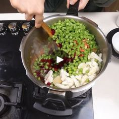 a person stirring vegetables in a pot on the stove