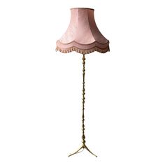 a floor lamp with a pink shade on it's base and beaded trim