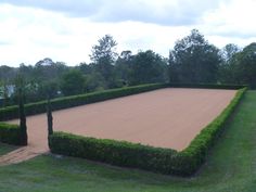 a large garden with hedges and trees in the middle