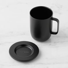 a black coffee cup and saucer on a marble surface