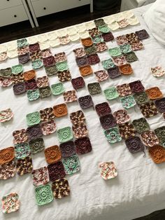 a quilted table top with many squares and flowers on it, sitting on a bed