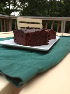 a piece of chocolate cake sitting on top of a white plate next to a green napkin