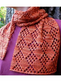 a woman wearing a knitted scarf with an orange design on the top and bottom