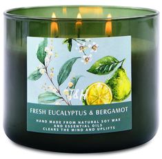 a candle that is sitting in front of a glass container with lemons and leaves on it