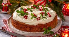 a cake with white frosting and cranberries on a plate next to candles