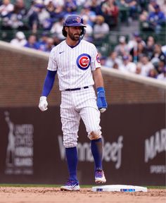 a baseball player standing on top of a base in front of a crowd at a game