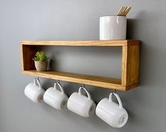 a wooden shelf with four mugs hanging on it