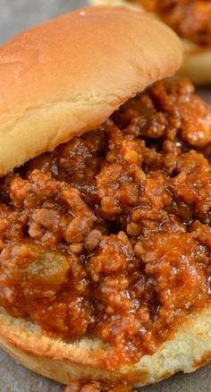 a sloppy joe sandwich sitting on top of a bun next to another sandwich with meat in it