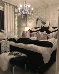 a black and white bedroom with a chandelier hanging from the ceiling, pillows on the bed