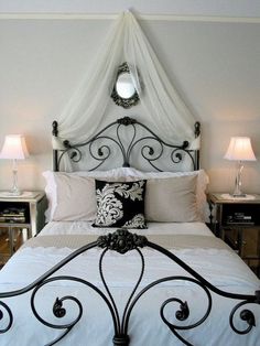 a bed with white sheets and pillows in a bedroom next to two nightstands on either side of the bed