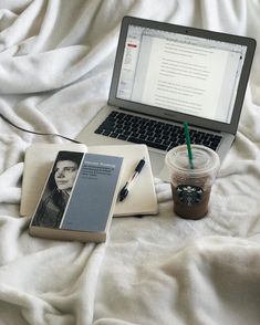 an open laptop computer sitting on top of a bed next to a cup of coffee