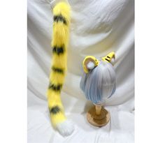 a yellow and black cat tail next to a wig