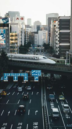 a train traveling over a bridge in the middle of a busy city with lots of traffic