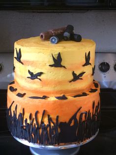 a three tiered cake decorated with black birds and orange frosting, on top of a stove