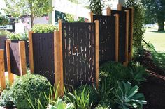 a wooden fence surrounded by green plants and bushes in a yard with the words cut deco written on it