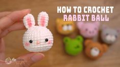 a hand holding a tiny crochet rabbit ball in front of small stuffed animals