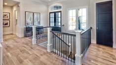 a large open floor plan with wood floors and white walls, black railings and windows