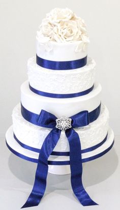 a three tiered wedding cake with blue ribbon and white flowers on the top layer